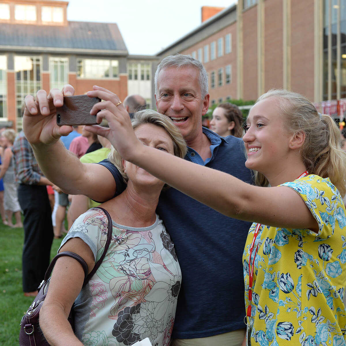 A mother, father, and daughter taking a selfie with a cellphone during Move In Day at Denison University.