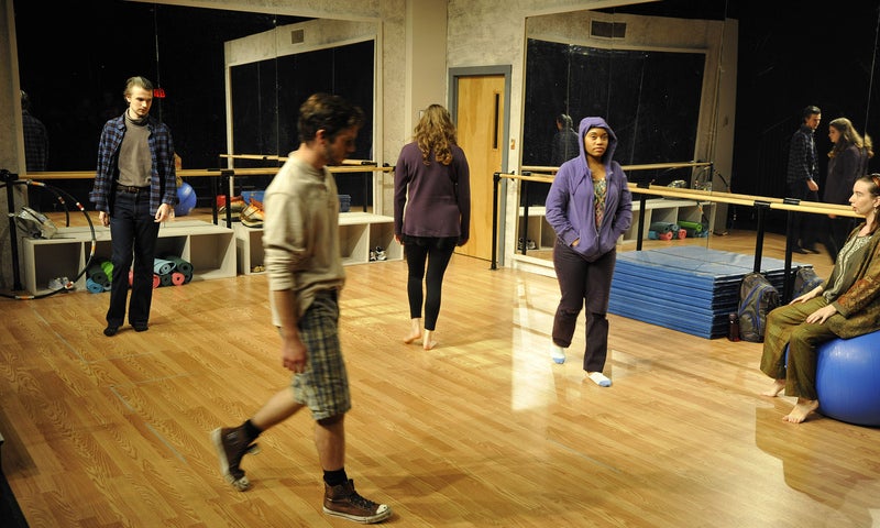 Marty sits on a yoga ball as she watches the class walk the space at the start of an acting exercise.