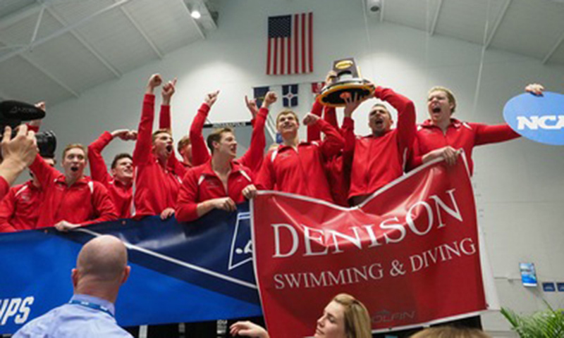 Men's swim and dive team with trophy and banner