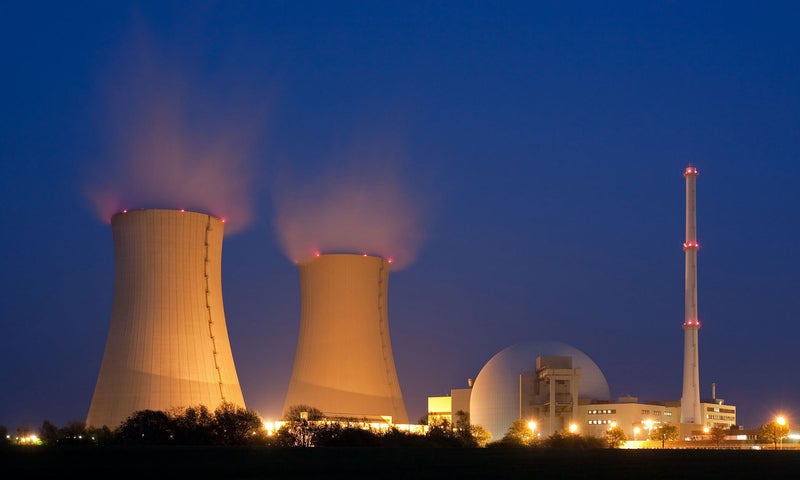 Picture of a factory at night, releasing smoke into the air