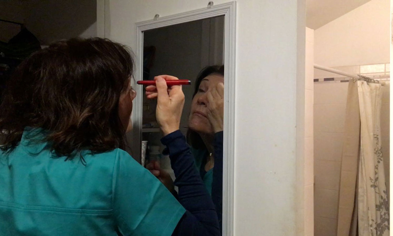 Woman in front of mirror putting on makeup