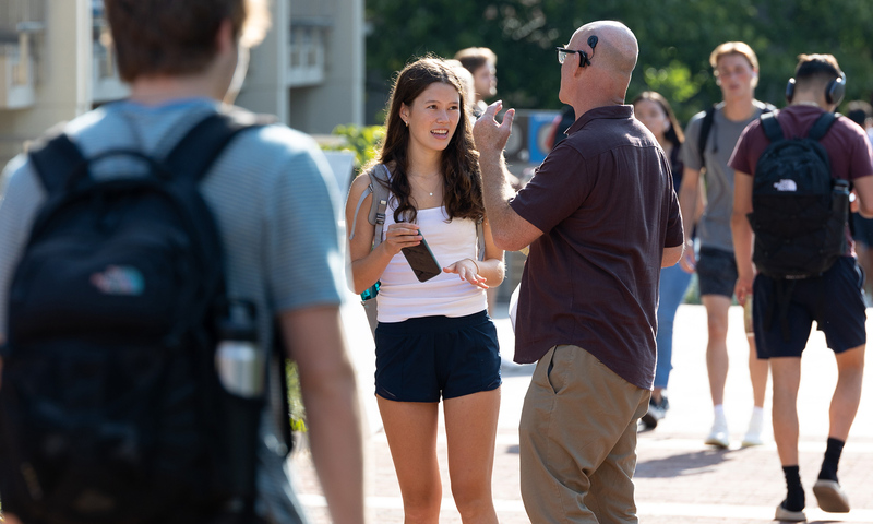 Student and faculty member talking to each other on the academic quad