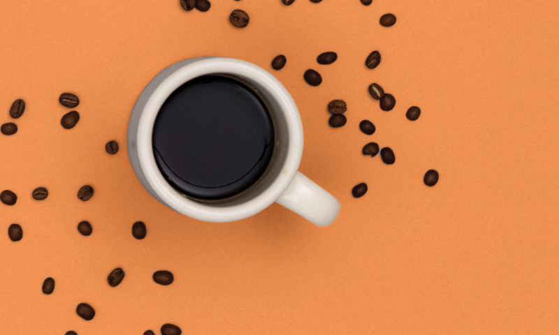 Coffee cup with beans on an orange background