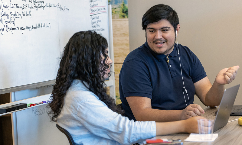 Two students talking at a desk