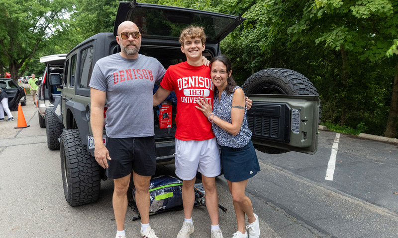 A famiily standing in behind a vehicle with an open door