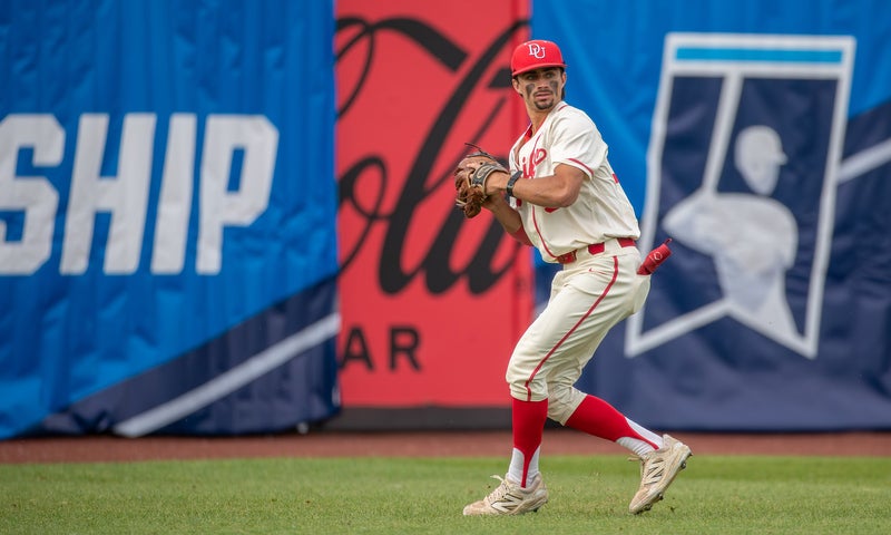 A college baseball player, Eric Colaco ’25, in uniform fielding a ball in a game.
