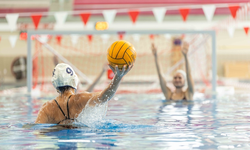 Women in a swimming pool playing water polo.