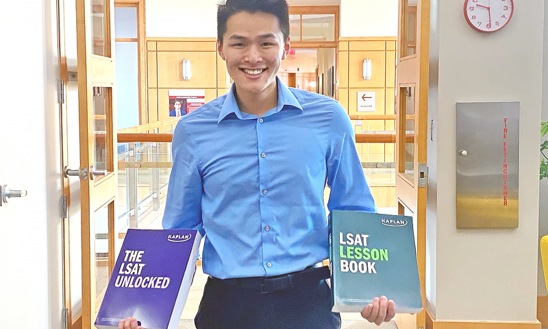 Alex Pan ’23 poses for a photo with Kaplan course materials.