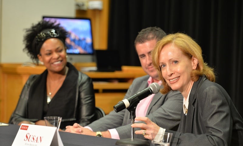 Susan Booth '85 sits at a table in front of a microphone