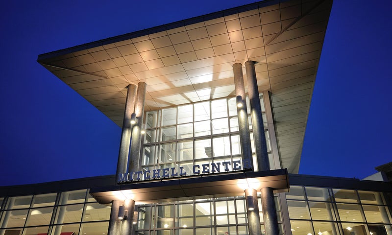 The front of the Mitchell Center is lit up by lights.