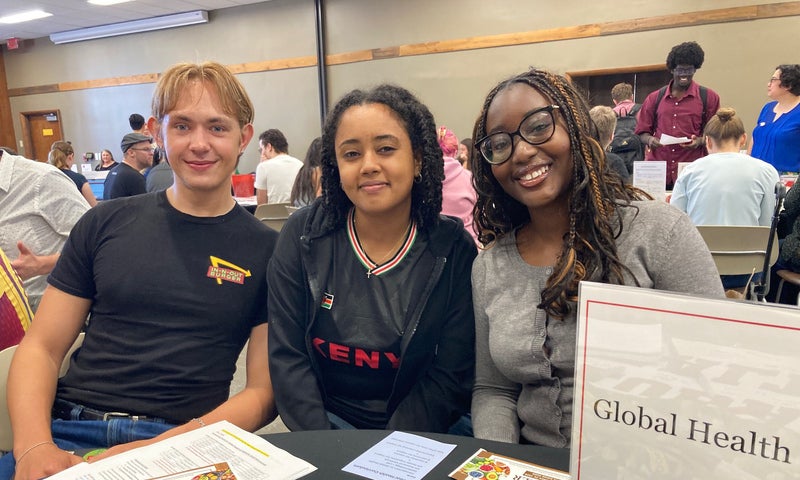 Three Global Heath majors seated at their information table at Denison's Major Day.