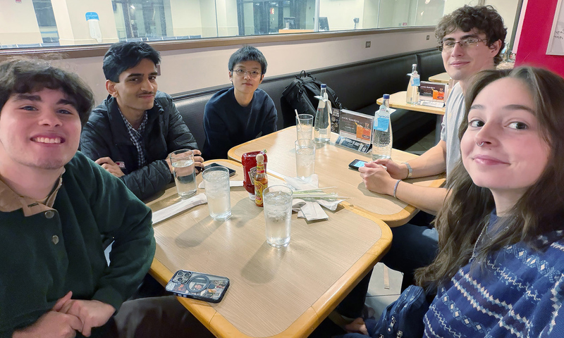 Five young people sitting together at a restaurant booth.
