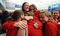 Denison swimmers embrace senior co-captain Tara Culibrk clutching a trophy.