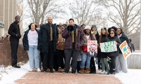 Tewoflos Tewoldeberhan ’25 and Thomas Coffey ’25, both wearing ties, lead the march from Slayter Hall to Mitchell Center. 
