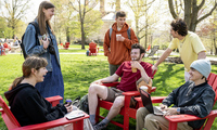 Picture of college students sitting on chairs outside and having a conversation