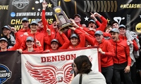 Denison swim and dive team celebrates on the podium with their trophy.