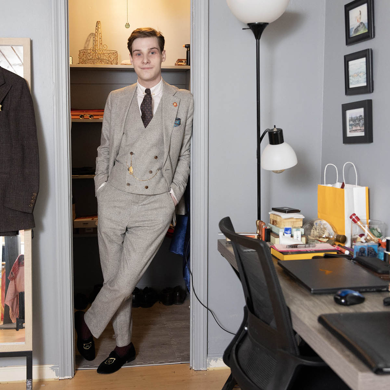 Sam Cuyler leaning against a door frame wearing a three-piece suit.