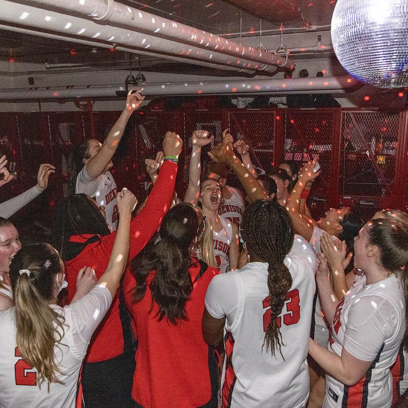 Denison Women's basketball team cheer under the lights of a disco ball spinning in their locker room before a game.