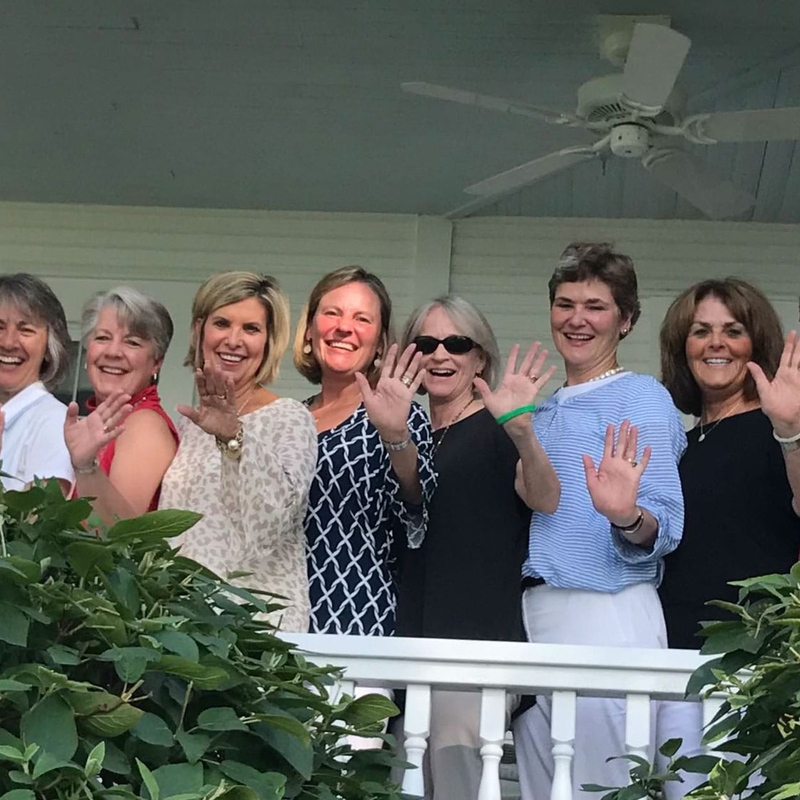 Women posing on porch waving hands