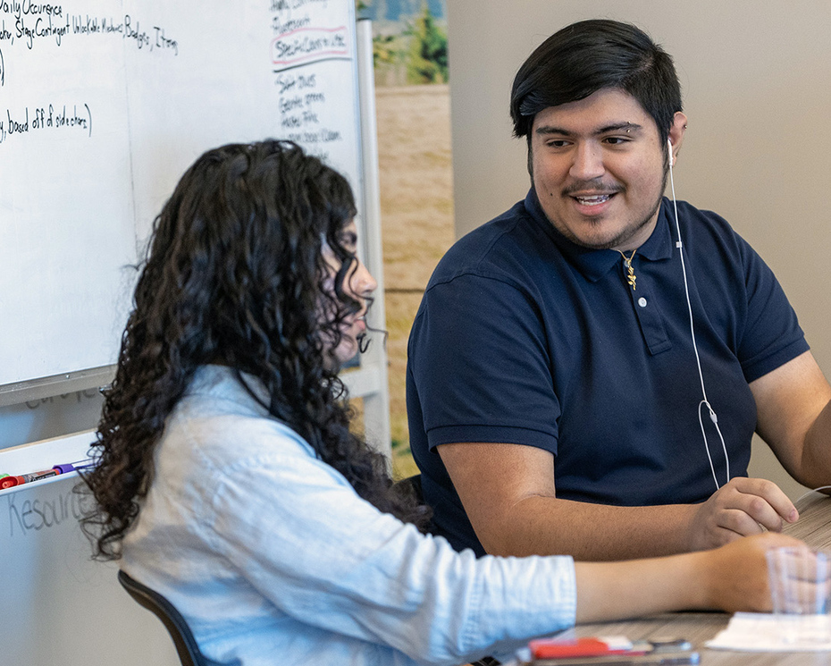 Two students talking at a desk