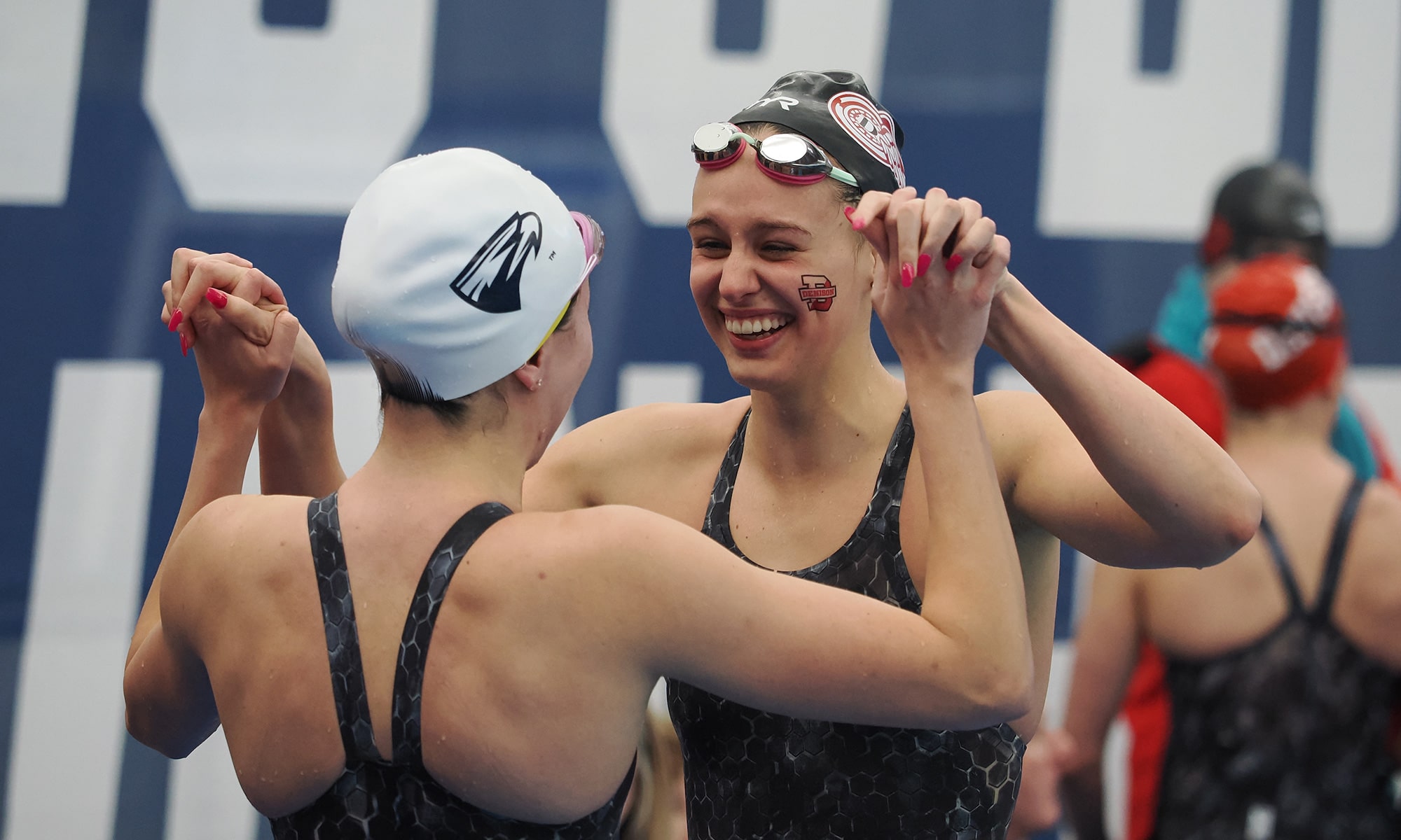 Denison swim & dive team members holding hands and celebrating