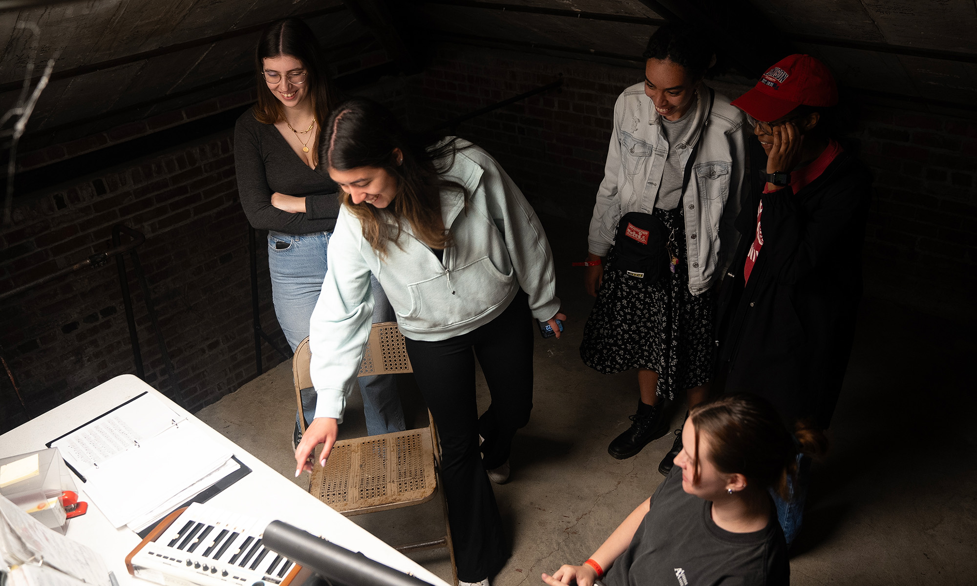 A small group of people looking at a mini keyboard in a dark room. 