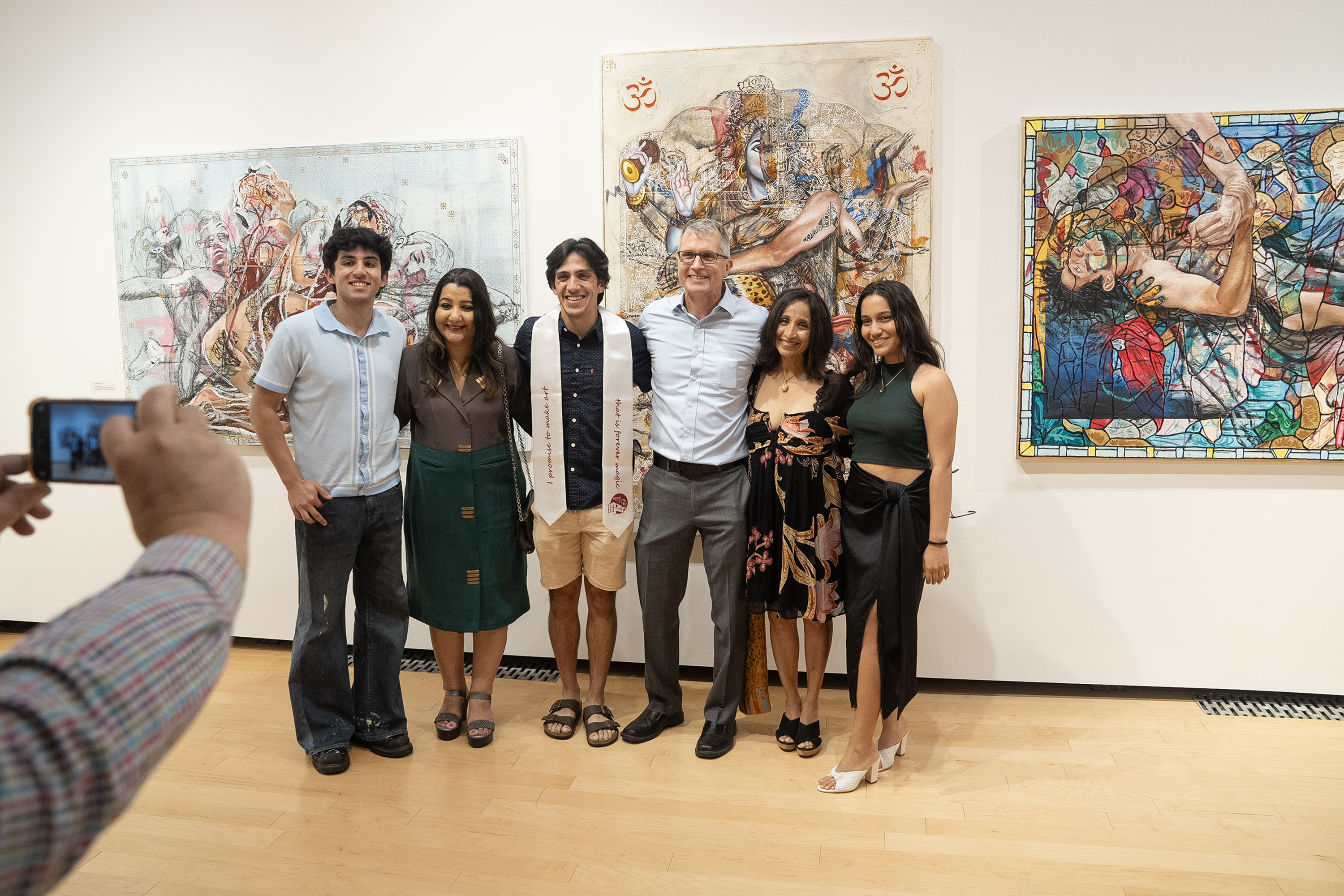 Nadeem Jones and his family pose for a cell phone picture while standing in front of his triptych art piece at the Denison Museum.
