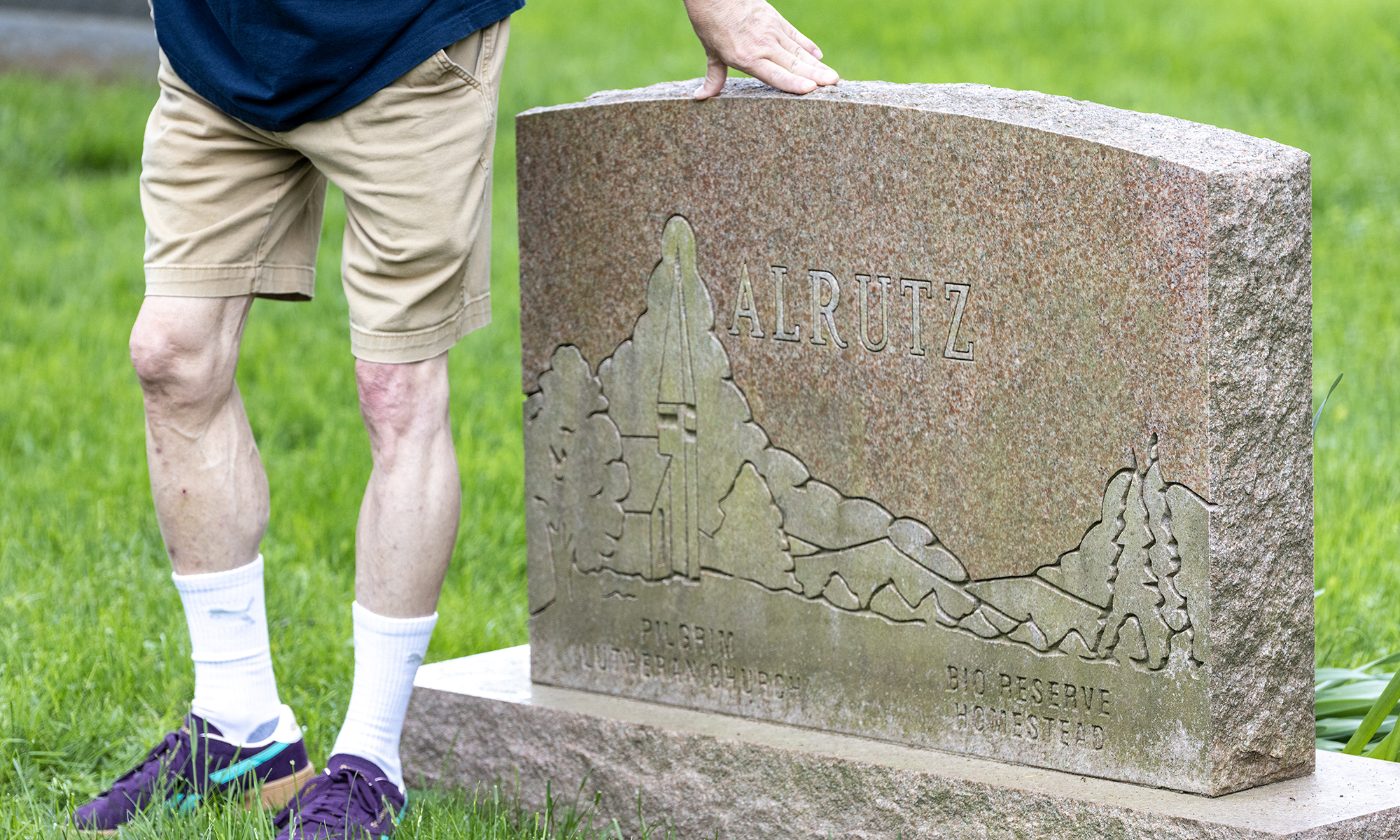 A professor poses near a gravestone.
