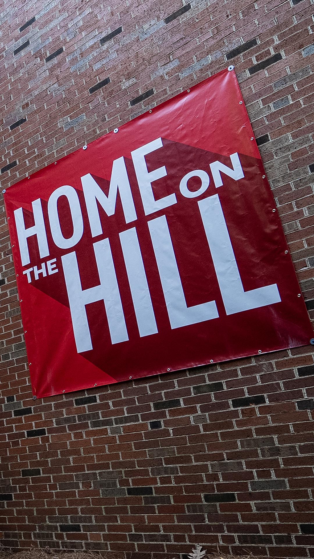 Red banner on a brick building that reads "Home on The Hill"