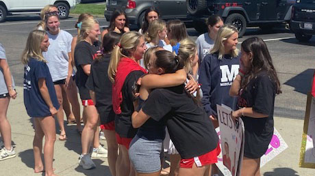 Students hug before getting on the bus.