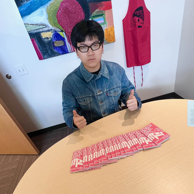 Duc Le ’26 with booklets he designed.