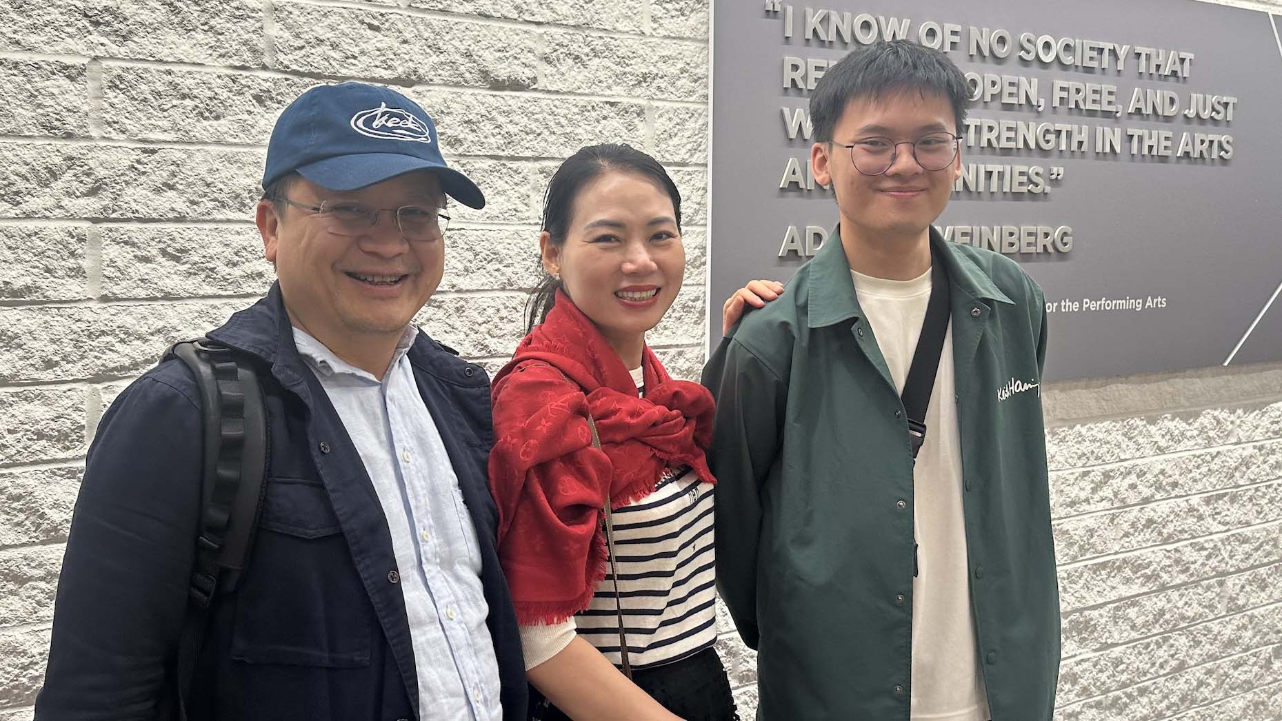 A student and his parents take a photo in front of the Eisner Center.