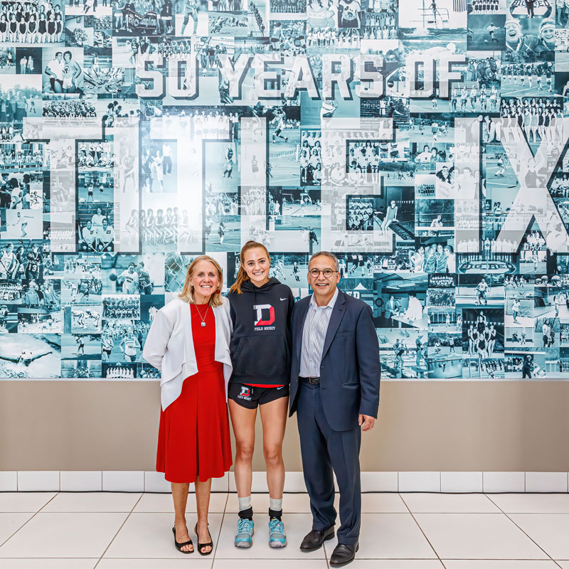 Nan, Kate Hinshaw, and Adam Weinberg in front of the Title IX billboard.