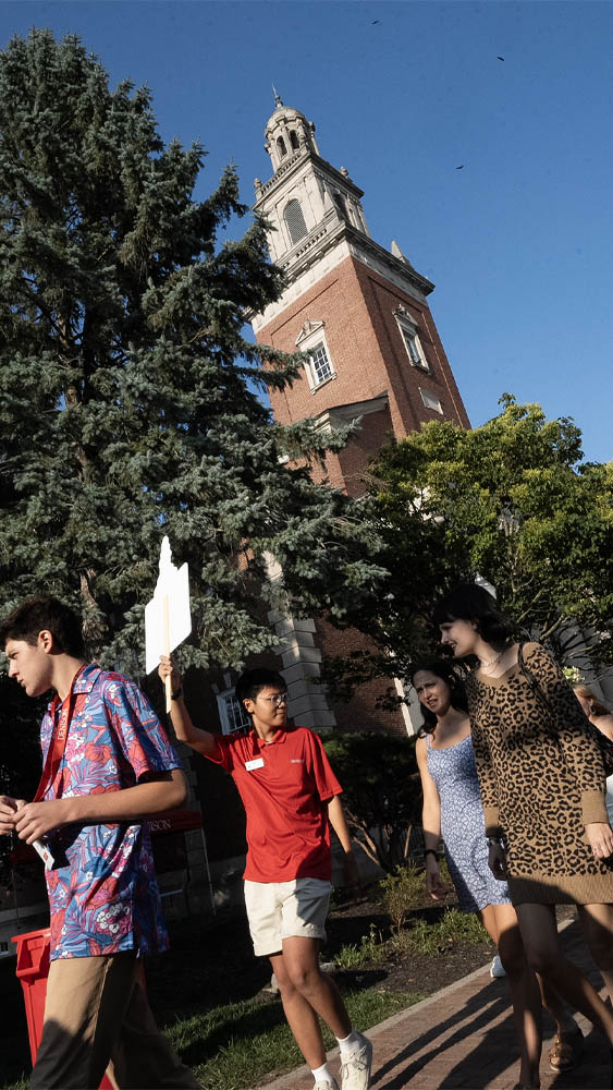 A new student orientation leader guides first-year students down Chapel Walk in front of Swasey Chapel to an orientation session.