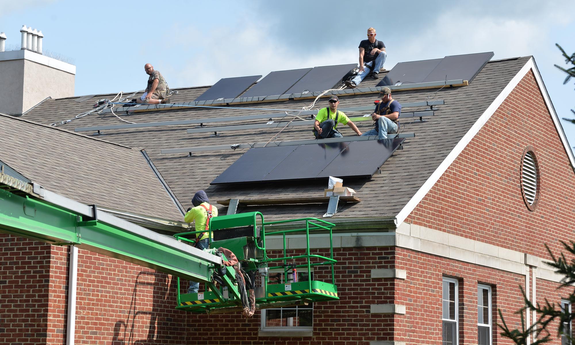 A crew installs solar panels on a rooftop.
