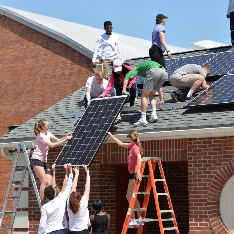 A crew installs solar panels on a rooftop.