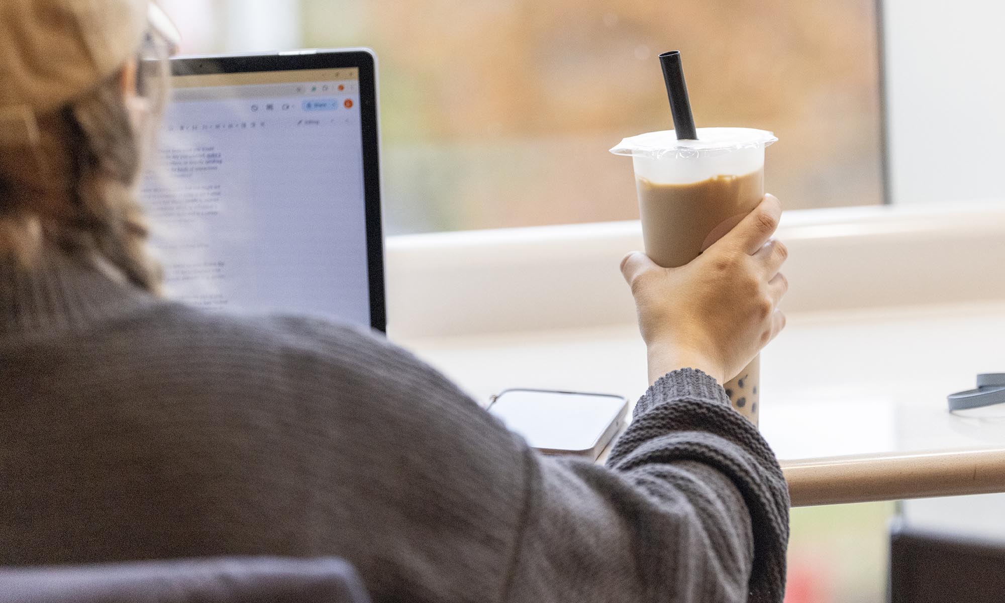 Photo of a customer sitting with their laptop and a boba tea at Trucha.